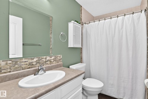 Vanity with integrated sink, chrome faucet, and mosaic tile backsplash - 16808 100 Street Nw, Edmonton, AB - Indoor Photo Showing Bathroom