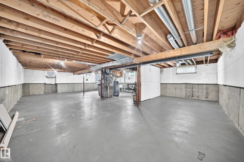 Unfinished basement with exposed wood joists and concrete walls, featuring a painted concrete floor and visible utility lines - 16808 100 Street Nw, Edmonton, AB - Indoor Photo Showing Basement