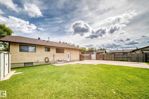 Expansive rear yard featuring green lawn, a paved driveway, and perimeter wood fencing - 16808 100 Street Nw, Edmonton, AB - Outdoor