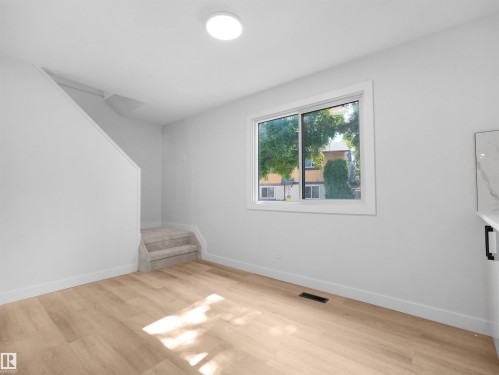 Recessed ceiling lighting, wood-finish flooring, white walls, and a large window with white trim - 126 Woodstock Nw, Edmonton, AB - Indoor Photo Showing Other Room