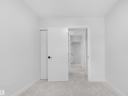 Neutral carpeted flooring, white walls, and a flat-panel door with matte black hardware - 126 Woodstock Nw, Edmonton, AB - Indoor Photo Showing Other Room