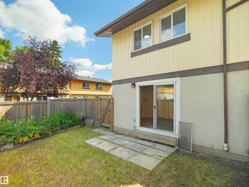 Rear exterior with sliding glass door, patio pavers, and wood privacy fencing - 126 Woodstock Nw, Edmonton, AB - Outdoor With Exterior