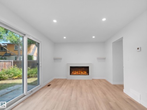 Recessed lighting illuminates wood-finish flooring - 126 Woodstock Nw, Edmonton, AB - Indoor With Fireplace