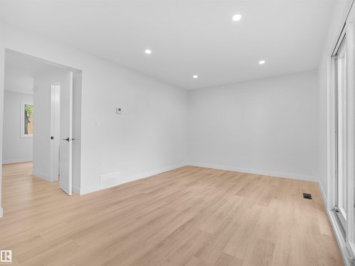 Recessed lighting, light wood-finish flooring, white walls, and a sliding glass door - 126 Woodstock Nw, Edmonton, AB - Indoor Photo Showing Other Room