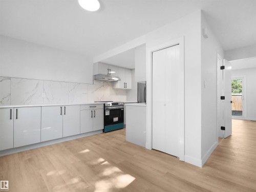 Light wood-finish flooring throughout, modern kitchen with white cabinetry, stainless steel range hood, and marble-look backsplash - 126 Woodstock Nw, Edmonton, AB - Indoor Photo Showing Kitchen