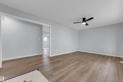 Spacious room featuring light gray walls, wood-finish flooring, and white baseboards - 9416 153 Street Nw, Edmonton, AB - Indoor Photo Showing Other Room