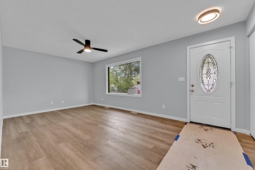 Entryway featuring wood-finish flooring, light gray walls, a white front door with an oval leaded glass insert, and a modern flush-mount light fixture - 9416 153 Street Nw, Edmonton, AB - Indoor Photo Showing Other Room