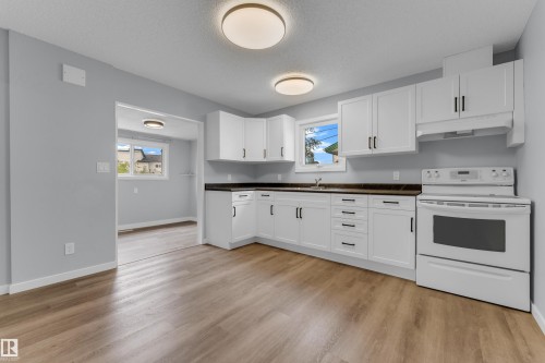 Kitchen featuring white cabinetry, dark countertops, a built-in range, wood-finish flooring, and recessed lighting - 9416 153 Street Nw, Edmonton, AB - Indoor Photo Showing Kitchen