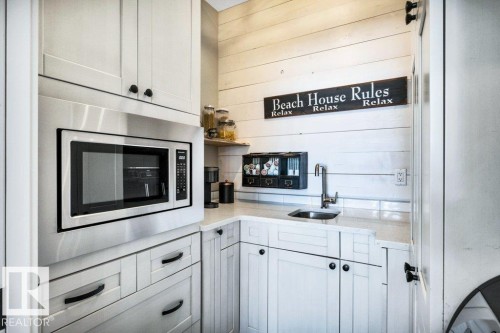 Butlers Pantry Boasts Built-in stainless steel microwave, white shaker-style cabinetry, light-toned countertop,  horizontal wood paneling - 180 Crystal Springs Drive, Rural Wetaskiwin County, AB - Indoor Photo Showing Kitchen