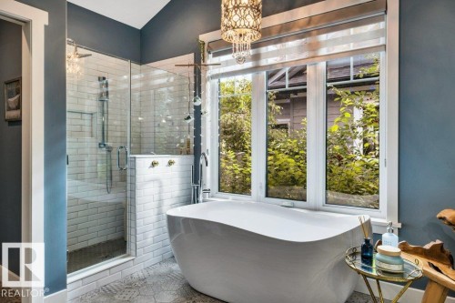 The Luxurious ensuite showcases a Freestanding oval tub, glass-enclosed shower with subway tile, large multi-pane window, decorative overhead light fixture - 180 Crystal Springs Drive, Rural Wetaskiwin County, AB - Indoor Photo Showing Other Room