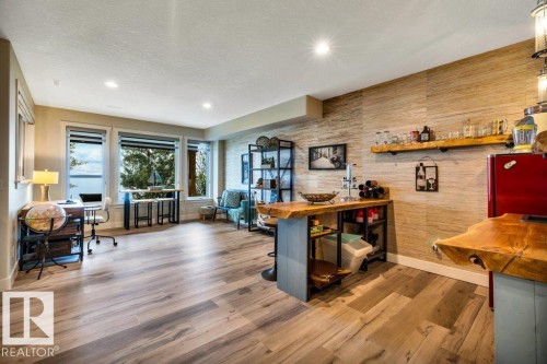 Wood-finish flooring throughout, featuring a custom wood-slab bar with built-in shelving, and a textured accent wall - 180 Crystal Springs Drive, Rural Wetaskiwin County, AB - Indoor