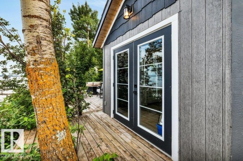 Exterior featuring wood-look siding, dark shaker shingle accent, and double French doors with white trim on this great boat house used as an additional entertainment area. - 180 Crystal Springs Drive, Rural Wetaskiwin County, AB - Outdoor