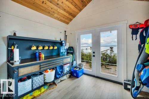 Vaulted wood-paneled ceiling, light wood-finish flooring, white shiplap walls, and double French doors opening to a deck - 180 Crystal Springs Drive, Rural Wetaskiwin County, AB - Indoor