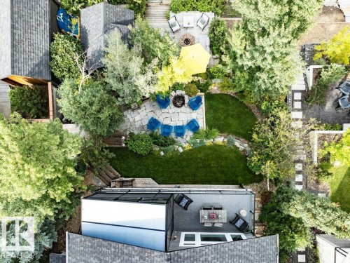 Expansive multi-level rear yard featuring a stone patio, manicured lawn, mature trees, and a ground-level deck - 180 Crystal Springs Drive, Rural Wetaskiwin County, AB - Outdoor