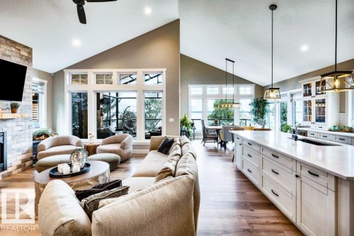 Vaulted ceilings, wood-finish flooring, stone-clad fireplace, massive kitchen island in the open concept main living space - 180 Crystal Springs Drive, Rural Wetaskiwin County, AB - Indoor Photo Showing Living Room With Fireplace