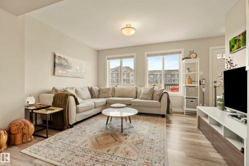 Wood-finish flooring, white walls, and a contemporary ceiling light fixture - 4013 Blackbird Link Nw, Edmonton, AB - Indoor Photo Showing Living Room