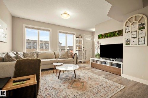 Expansive living area with large windows, wood-finish flooring, and light-toned walls - 4013 Blackbird Link Nw, Edmonton, AB - Indoor Photo Showing Living Room