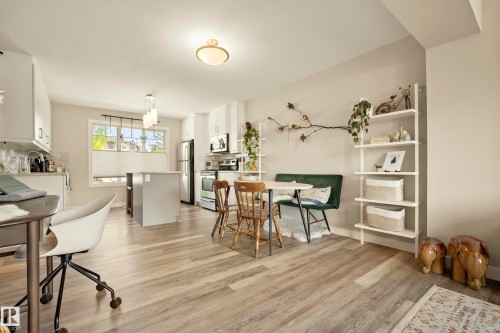 Wood-finish flooring throughout, kitchen with white cabinetry, stainless steel appliances, and a central island - 4013 Blackbird Link Nw, Edmonton, AB - Indoor Photo Showing Dining Room