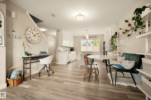 Spacious room featuring wood-finish flooring, a built-in kitchen with white cabinetry, and recessed lighting - 4013 Blackbird Link Nw, Edmonton, AB - Indoor Photo Showing Dining Room