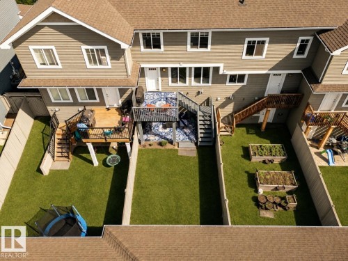 Exterior siding with multiple windows, two outdoor decks, fenced yards with artificial turf, and raised garden beds - 4013 Blackbird Link Nw, Edmonton, AB - Outdoor With Exterior