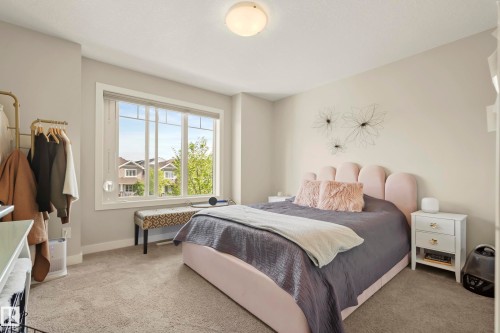 Bright bedroom with a large multi-pane window, flush-mount ceiling light, and light-toned wall-to-wall carpeting - 4013 Blackbird Link Nw, Edmonton, AB - Indoor Photo Showing Bedroom