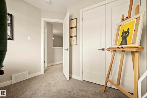 Neutral tone wall paint, light gray carpeting, white interior doors, contemporary door hardware, and a ceiling-mounted smoke detector - 4013 Blackbird Link Nw, Edmonton, AB - Indoor Photo Showing Other Room