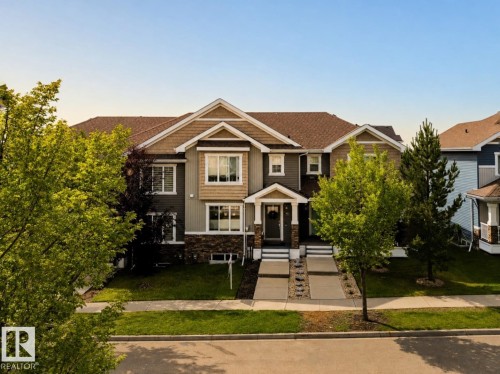 Multi-level property exterior with varied siding textures, stone accents, multiple windows, covered entry, and concrete pathways - 4013 Blackbird Link Nw, Edmonton, AB - Outdoor With Facade