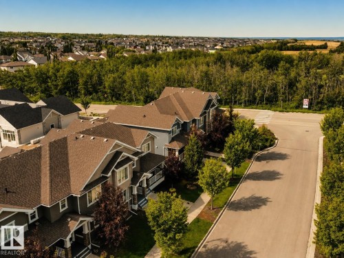 Tree-lined street with residential properties featuring gabled roofs and mature landscaping - 4013 Blackbird Link Nw, Edmonton, AB - Outdoor With View