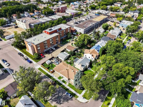 Aerial view showcasing a brick multi-unit residential building with mature landscaping, expansive green space, and established tree coverage - 9402 117 Avenue Nw, Edmonton, AB - Outdoor With View