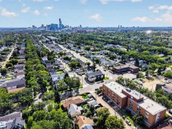 Aerial perspective of a tree-lined residential area with urban skyline backdrop - 