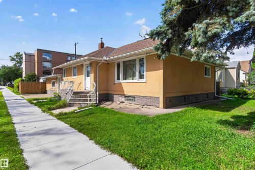Siding exterior with a shingled roof, multiple windows, and a concrete pathway - 9402 117 Avenue Nw, Edmonton, AB - Outdoor