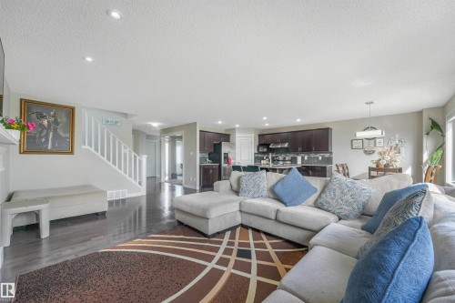 Recessed ceiling lighting, wood-finish flooring, white staircase with railing, dark wood-finish kitchen cabinetry, stainless steel kitchen appliances - 3359 13 Avenue Nw, Edmonton, AB 