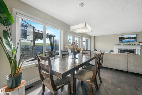 Open-concept living space with dark wood-finish flooring, a contemporary rectangular light fixture, and large windows providing abundant natural light - 3359 13 Avenue Nw, Edmonton, AB 