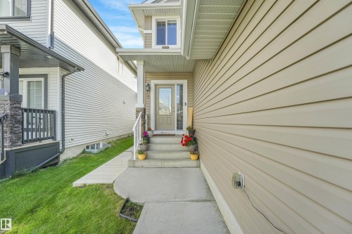 Front entry with concrete pathway and steps, covered porch, and exterior lighting - 3359 13 Avenue Nw, Edmonton, AB 