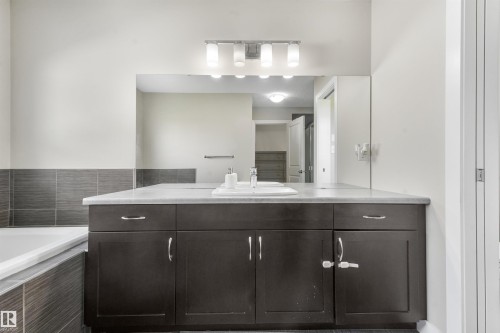 Dark wood-finish vanity with a light-toned countertop and an integrated sink - 3359 13 Avenue Nw, Edmonton, AB 