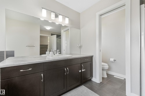 Dark wood-finish vanity with a light-toned countertop, rectangular undermount sink, and chrome fixtures - 3359 13 Avenue Nw, Edmonton, AB 