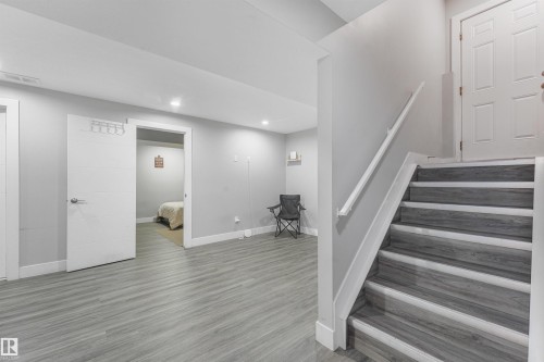 Gray wood-finish flooring, white trim, recessed lighting, and a white handrail - 3359 13 Avenue Nw, Edmonton, AB 