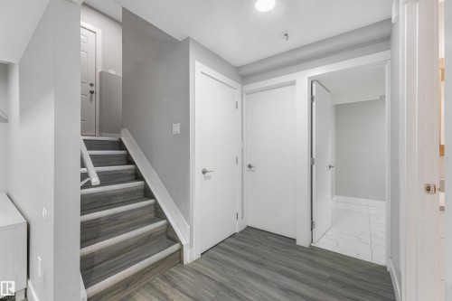 Wood-finish flooring, staircase with white risers, recessed lighting, and white interior doors - 3359 13 Avenue Nw, Edmonton, AB 