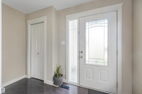 Entryway featuring a white door with decorative glass inserts, a coordinating sidelight, and dark wood-finish flooring - 3359 13 Avenue Nw, Edmonton, AB 