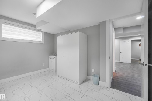 Large format white tile flooring with gray veining, gray painted walls, and a white framed horizontal window with blinds - 3359 13 Avenue Nw, Edmonton, AB 