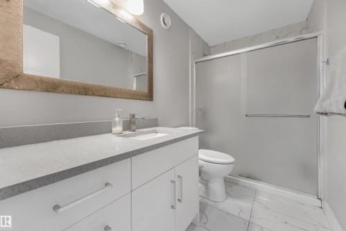 White vanity with a light gray countertop, rectangular undermount sink, and a framed mirror - 3359 13 Avenue Nw, Edmonton, AB 
