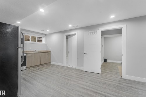 Recessed lighting illuminating the wood-finish flooring, a functional kitchenette with built-in cabinetry, and integrated stainless steel appliances - 3359 13 Avenue Nw, Edmonton, AB 