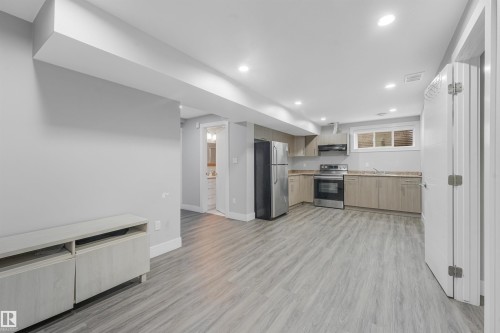 Recessed lighting, wood-finish flooring, stainless steel appliances, light wood-finish cabinetry, and a full-size window - 3359 13 Avenue Nw, Edmonton, AB 