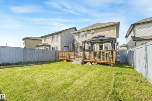 Expansive backyard with a wooden fence, a spacious deck, and a gazebo, complementing the home's vinyl siding - 3359 13 Avenue Nw, Edmonton, AB 