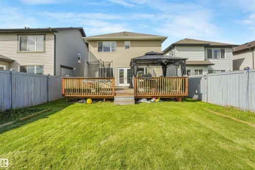 Expansive backyard featuring a lush lawn, wooden privacy fencing, and a multi-level deck with a gazebo - 3359 13 Avenue Nw, Edmonton, AB 