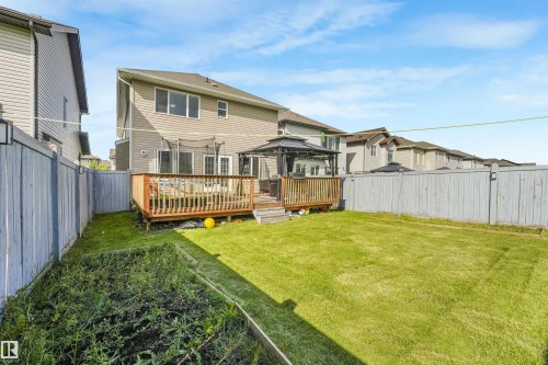 Expansive grass lawn with raised garden bed, private fenced perimeter, and a wooden deck featuring a gazebo - 3359 13 Avenue Nw, Edmonton, AB 