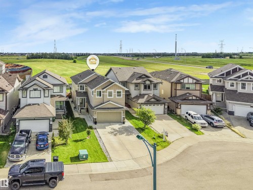 Aerial view of this two-story residence featuring a three-car garage, concrete driveway, and manicured front lawn - 3359 13 Avenue Nw, Edmonton, AB 