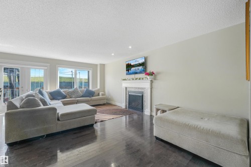 Dark wood-finish flooring, white fireplace mantel with decorative tile surround, recessed lighting, and white trim - 3359 13 Avenue Nw, Edmonton, AB 