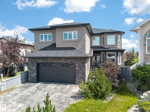 Contemporary stucco exterior with a stone veneer accent, attached garage, double-door entry, and multiple windows - 7103 168 Avenue Nw, Edmonton, AB - Outdoor