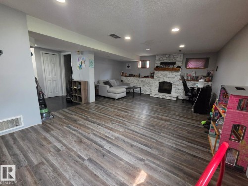 Wood-finish flooring, white stone-clad fireplace with mantel, recessed lighting, and light gray wall paint - 3511 28 Avenue Nw, Edmonton, AB - Indoor